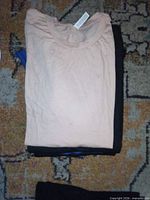 Stack of three folded Canvas t-shirts in light pink, black and blue