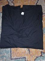 Folded black Canvas T-shirt with visible size tag