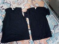 two black shirts laid flat, one sleeveless, one short sleeve