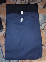 Navy blue t-shirt on top of a black t-shirt, showing colours and style