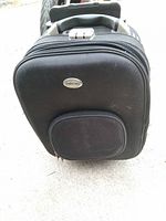 Front view of black Chido One suitcase showing badge and front pocket