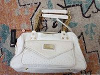 Overall view of white Christian Audigier faux ostrich handbag showing chain handles, front pocket, tag attached