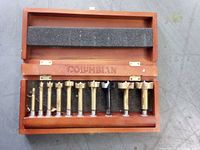 Open wooden case displaying ten Forstner bits in foam insert