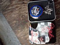 Open collector tin showing pocket watch with chain and Dale Earnhardt portrait dial alongside tin lid graphic
