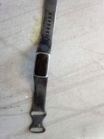 Top view of black Fitbit fitness tracker showing band, adjustment holes, display module, buckle end