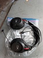 HyperX wired over-ear gaming headset on plastic bag showing earcups, cable, 3.5 mm plug and boom mic