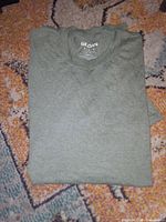 Folded green Gildan t-shirt displaying inside collar print