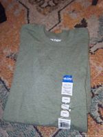 Folded sage green Gildan Heavy Cotton T-shirt with size and brand tags visible