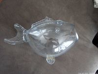 Side view of clear glass fish-shaped bowl showing tail, fins and body