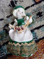 Full view of ceramic girl figurine showing color scheme, lace skirt and cornucopia