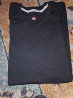 Folded black Hanes T-shirt showing collar tag and fabric condition