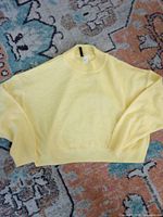 Front view of yellow H&M Divided sweater laid flat