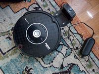 Top view of iRobot Roomba Pet Series vacuum with charging dock and power adapter