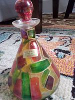 Full view of Murano glass bottle showing shape, mosaic pattern, stopper and label