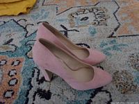 Pair of pink suede Jessica Simpson pumps displayed side by side on a patterned rug
