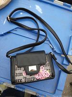 Front and strap of Juicy Couture purse on blue surface
