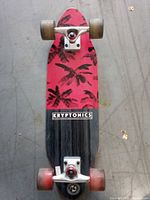 Underside of longboard showing palm leaf graphic, trucks and wheels