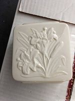 Top view of square ivory Lenox porcelain piece with raised tiger lily motif indicating pattern and material