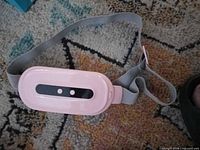 Front view of pink heating pad with control panel and grey strap