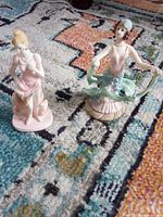 Both figurines shown together on patterned rug