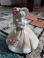 Front view of porcelain musical lady figurine showing gown, hat and roses