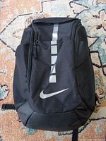 Front view of black Nike cooler backpack showing reflective stripe and swoosh logo