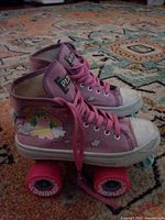 Side view of the pair of pink Pixie quad roller skates showing graphics, wheels, laces and wear