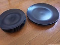 stack of five smaller black plates beside two larger black plates