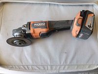 Side view of Ridgid cordless angle grinder with battery and disc