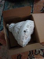 LED bulb in cardboard box, side view showing heat-sink fins