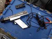 full view of timing light showing chrome body, inductive clamp, battery leads