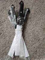 Four black-handled steak knives wrapped together, blades covered