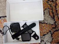open box showing smartwatch body, strap, charger cable