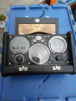 Open case showing front panel with speaker, tuning and clock gauges, world map in lid