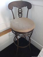 Front view of metal swivel bar stool showing seat, backrest, frame