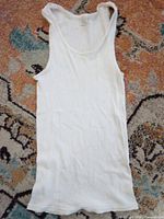 Full view of white ribbed tank top laid flat on patterned surface