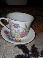Teacup on saucer showing floral pattern and gold trim