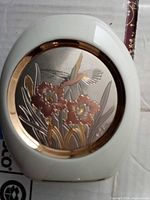 Front view of white porcelain vase with etched copper insert showing hummingbird and flowers