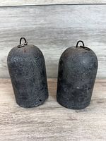 Front view of both cylindrical clock weights showing overall shape and surface wear