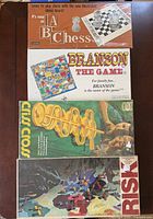 Stack of four boxed board games showing titles and artwork