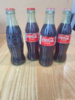 Front view of four sealed Coca-Cola bottles