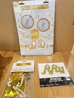 Sealed room decorating kit, foil banner package and cake topper displayed together
