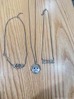 Three silver-tone necklaces laid flat showing pendants and chains