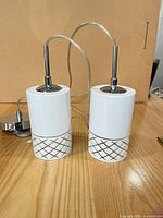Two white ceramic pendant lights standing upright on table