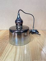 Pendant light resting on surface showing shade, chrome finial, cord, and canopy