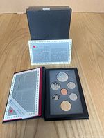 Open presentation case with coins, certificate, and outer sleeve visible