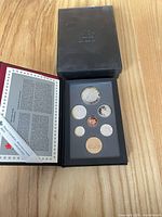 Closed black outer box with crown logo and open clamshell case showing coin set