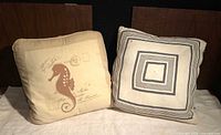 Two square throw pillows with seahorse and concentric square designs