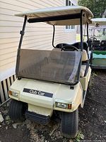 Front three-quarter view showing Club Car badge, windshield, roof, tires