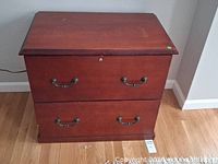 Front view of dark brown two-drawer file cabinet showing handles, lock and overall condition